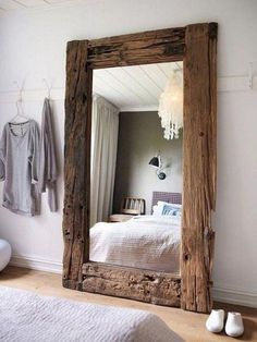 a bedroom with a large mirror on the wall and clothes hanging in front of it