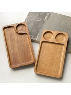 two wooden trays sitting on top of a table next to a book and knife