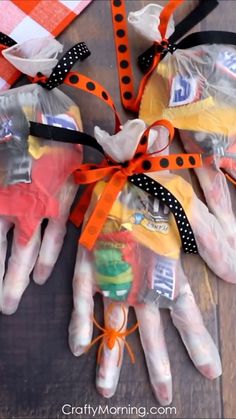 three plastic gloves with orange and black ribbons tied around them on top of a wooden table