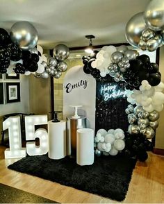 balloons and streamers decorate the entrance to an event with black, white and silver decorations