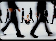 a woman sitting on the ground in front of a group of people with their legs crossed