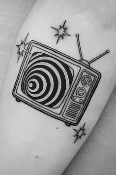 a black and white photo of a tv tattoo on the left arm with stars around it