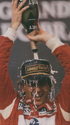 a man holding up a bottle in the air with water coming out of his mouth