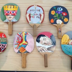 six paddles with different designs on them are hanging on a wall in front of a wooden table