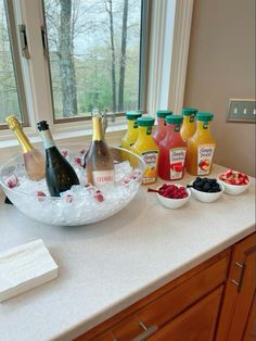 bottles of wine and fruit are sitting on the counter in front of a large window