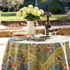 a table topped with a pie and wine glasses next to a vase filled with white roses