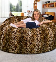 a woman laying on top of a leopard print bean bag chair in a living room