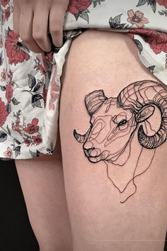 a woman's thigh with a tattoo of a ram and flowers on the side