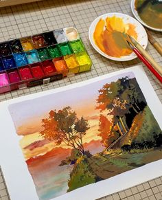 an artist's palette with watercolors and paintbrushes on the table