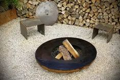 an outdoor fire pit with logs in the background