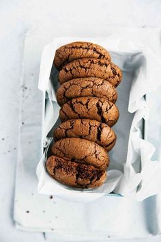 chocolate cookies stacked on top of each other in a white tray with parchment paper around them