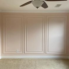 an empty room with a ceiling fan and beige paneled walls in the corner,