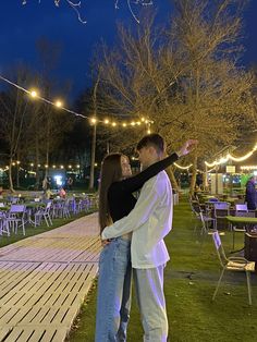 a man and woman standing next to each other in front of tables with lights on them