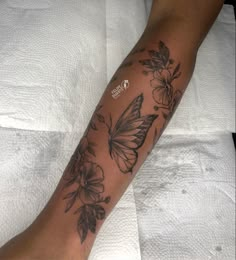 a person with a butterfly tattoo on their arm sitting on top of a white sheet