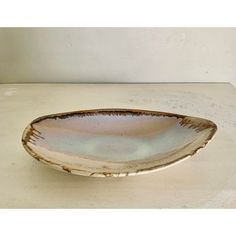 a white and brown bowl sitting on top of a table next to a black object