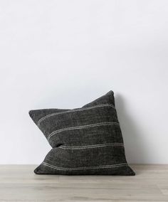 a black and white striped pillow sitting on top of a wooden floor next to a wall