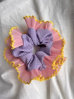 a pink and yellow scrunffle on top of a white cloth covered bed sheet