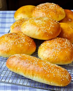 bread rolls cooling on a rack with sesame seed sprinkled on top, ready to be baked