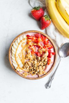 a bowl filled with granola, strawberries and bananas on top of a table