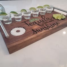 there is a wooden tray with drinks and donuts on it that says tequila, tequila, limes, and sunshades