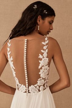 the back of a woman's wedding dress with flowers and pearls on her neck