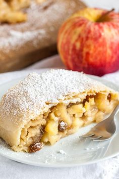 a piece of pie on a plate with an apple in the background and a fork next to it