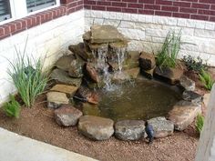 a small pond with rocks around it and water coming out of the top one side