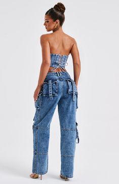 a woman wearing high waist jeans and a strapless top with cutouts on the back