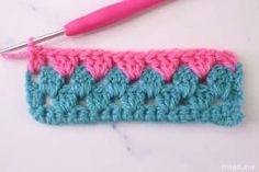 the crochet is being worked on with a pink and blue yarn ball next to it