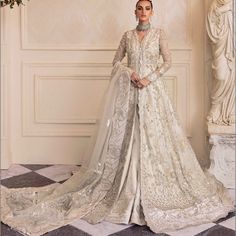 a woman in a white wedding gown standing on a checkered floor with an elaborate veil