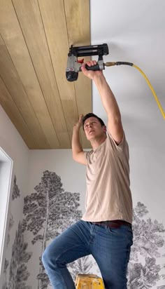 a man is using a power drill to paint the ceiling