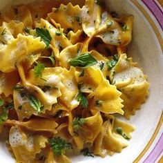 a white bowl filled with pasta covered in cheese and parsley on top of a table