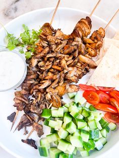 chicken skewers, cucumbers and tomatoes on a plate with ranch dressing