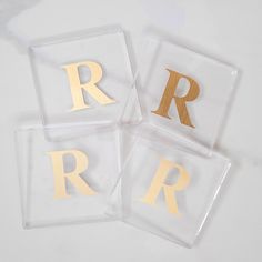 three clear coasters with gold foil letters on top of each one and the letter r