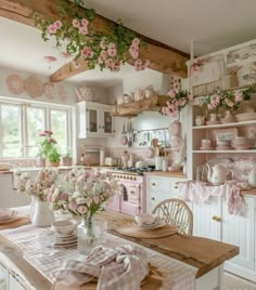 a kitchen with pink and white decor on the walls, flowers hanging from the ceiling