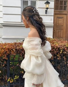 a woman is walking down the street wearing a white dress with ruffles on it