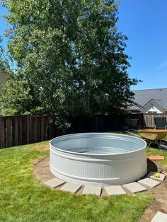 a large pool in the middle of a yard with grass around it and a tree