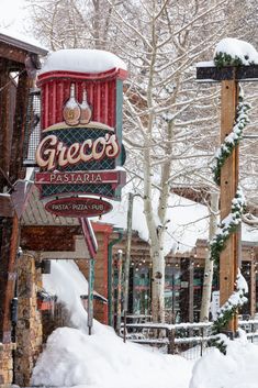 a restaurant sign covered in snow next to trees