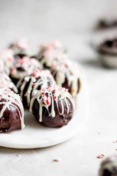 chocolate covered candies with white icing and sprinkles on a plate