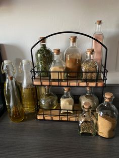 an assortment of different types of bottles on a shelf with spices and herbs in them