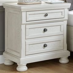 a white night stand with two drawers and a tray on it's end table