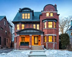 a large brick house with many windows and steps leading up to the front door on a snowy day