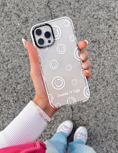 a woman holding up her phone case with smiley faces on it