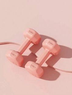 two pink dumbs sitting on top of each other next to a pair of headphones