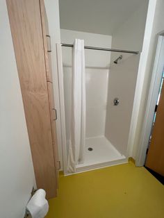 a bathroom with yellow flooring and a white shower