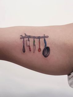 a person with a tattoo on their arm that has spoons and spatulas hanging from it