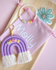 a wooden tray with a purple bag and some beads on it next to a keychain