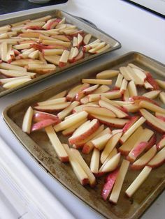 two pans filled with sliced apples sitting on top of a stove next to each other