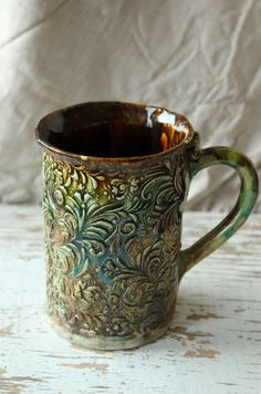 a brown and green cup sitting on top of a white table