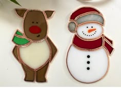 two decorated christmas cookies sitting on top of a white table next to a cup and saucer